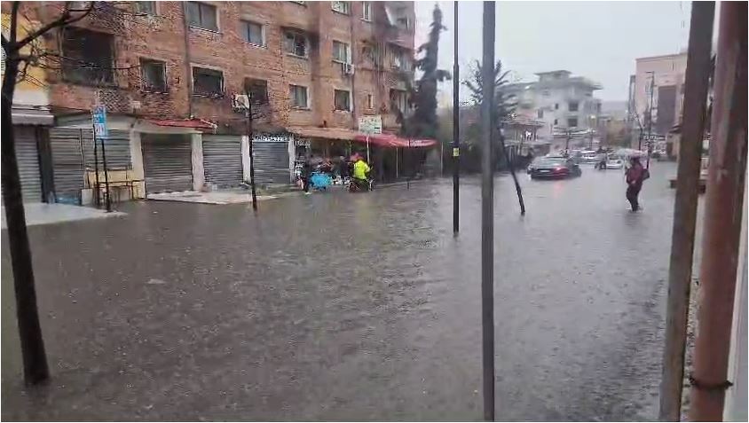 Përmbytet Durrësi! Qytetarja mbulon kokën me çadër të mos laget nga shiu, por uji i arrin deri në gjunjë! (PAMJET)